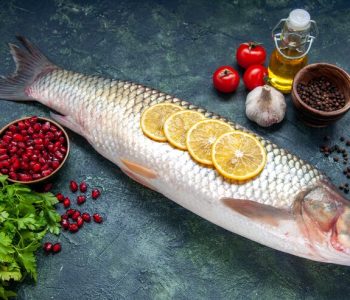 bottom-view-raw-fish-tomatoes-lemon-slices-oil-bottle-black-pepper-table_179666-43693